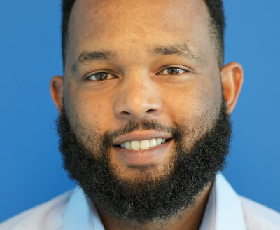 Smiling man with beard against blue background.